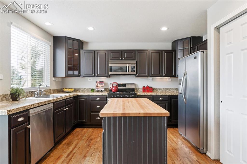 Image 13 of 40: Kitchen with glass insert cabinets, butcher block countertops, appliances w