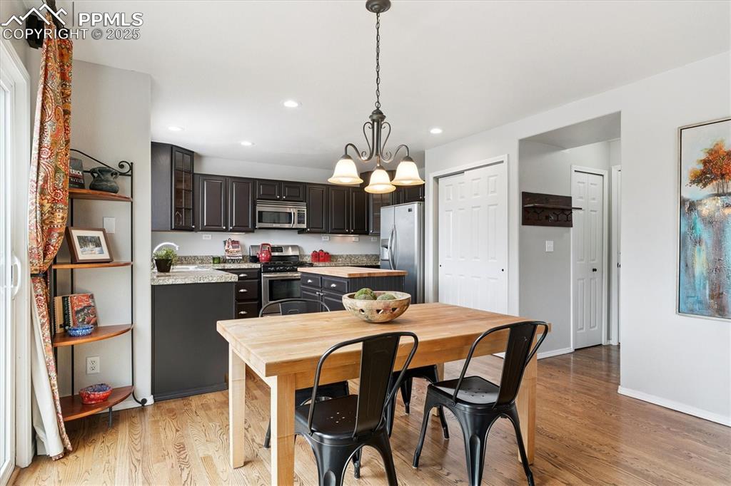 Image 14 of 40: Kitchen with light countertops, hanging light fixtures, light wood-style fl