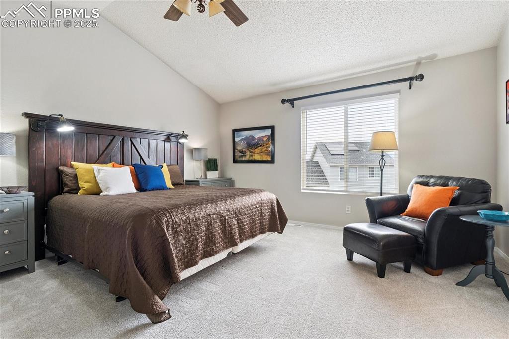 Image 24 of 40: Bedroom with lofted ceiling, light colored carpet, a textured ceiling, and 
