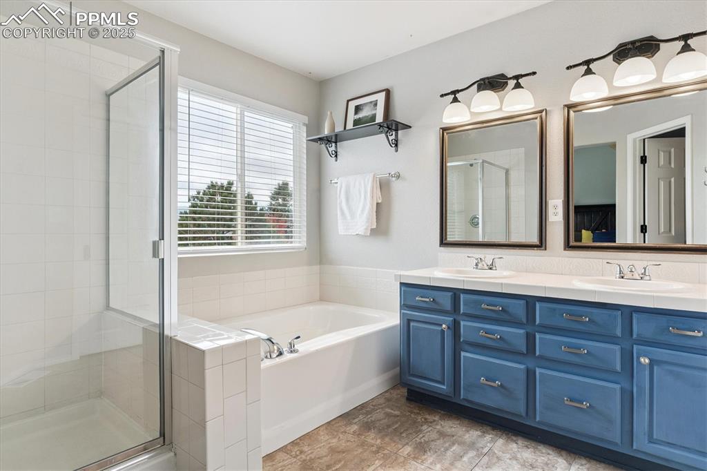 Image 28 of 40: Full bath with a garden tub, a stall shower, double vanity, and light tile 