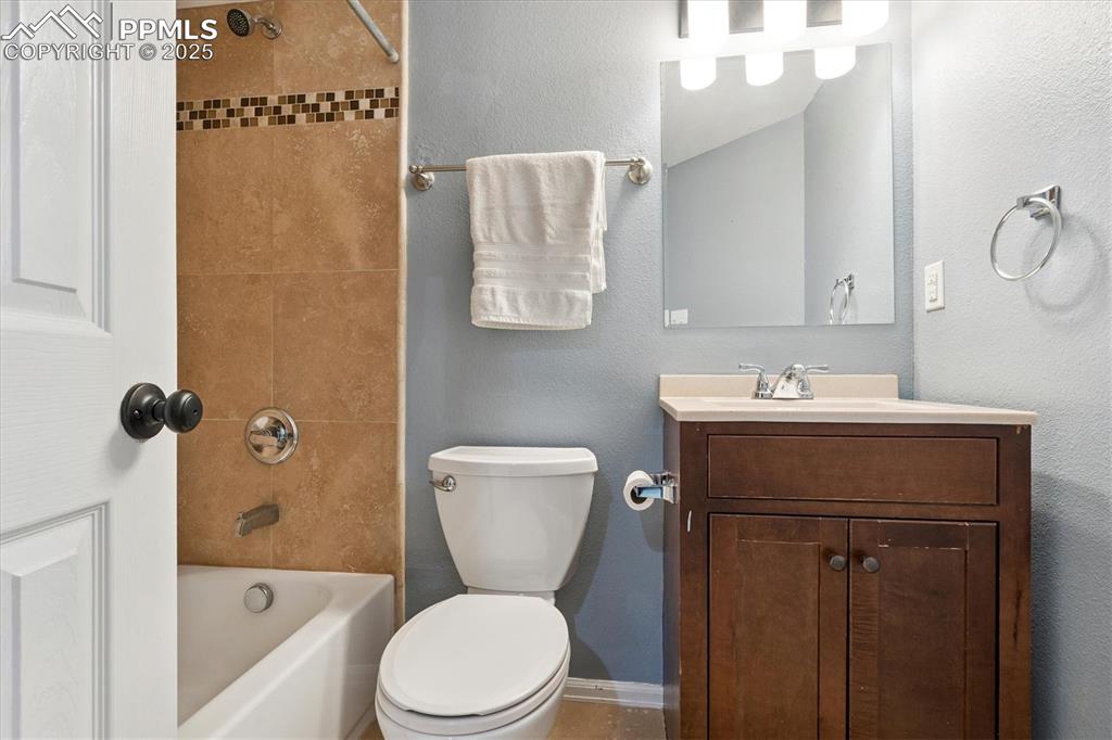 Image 33 of 40: Bathroom with a textured wall, vanity, and  shower combination
