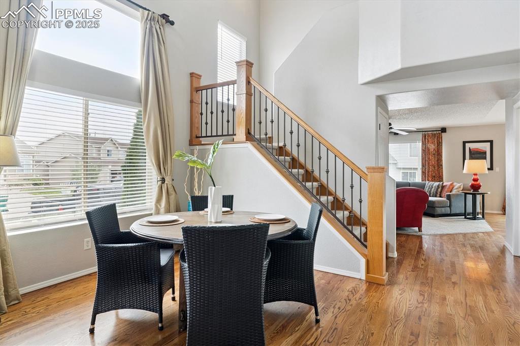 Image 6 of 40: Dining space with stairs, wood finished floors, and a towering ceiling