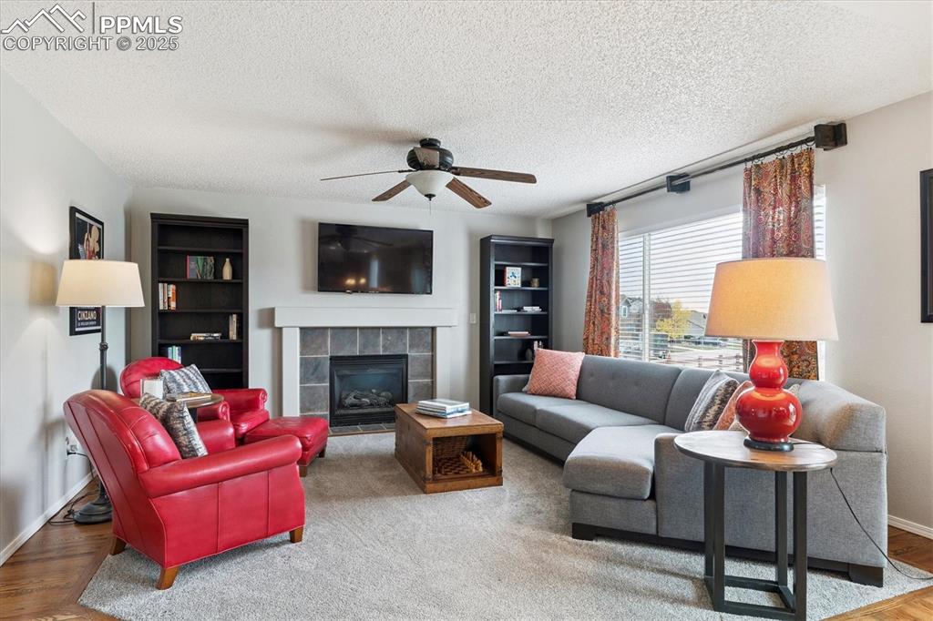 Image 9 of 40: Living area with wood finished floors, a tile fireplace, a textured ceiling