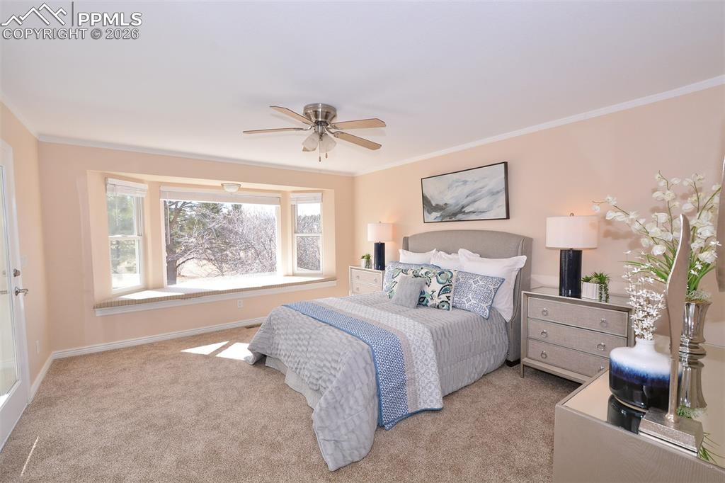 Image 22 of 50: Lovely master bedroom with window seat and ceiling fan.