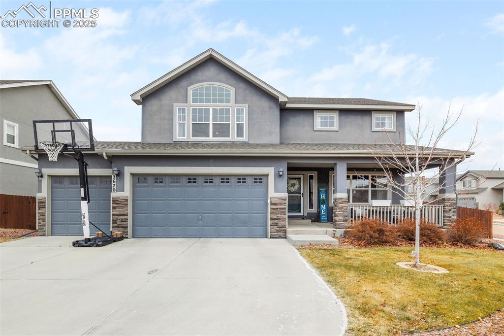 Caption: View of front of house featuring stone siding, stucco siding, a porch, concrete driveway, and a gara