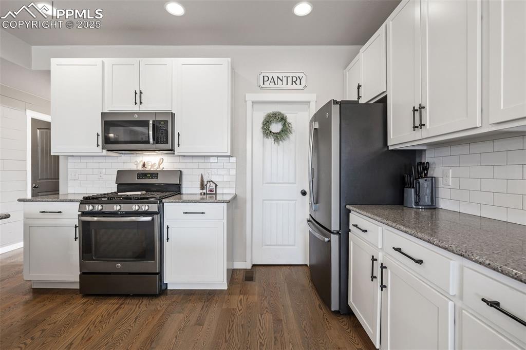Image 12 of 43: Kitchen with appliances with stainless steel finishes, white cabinetry, lig