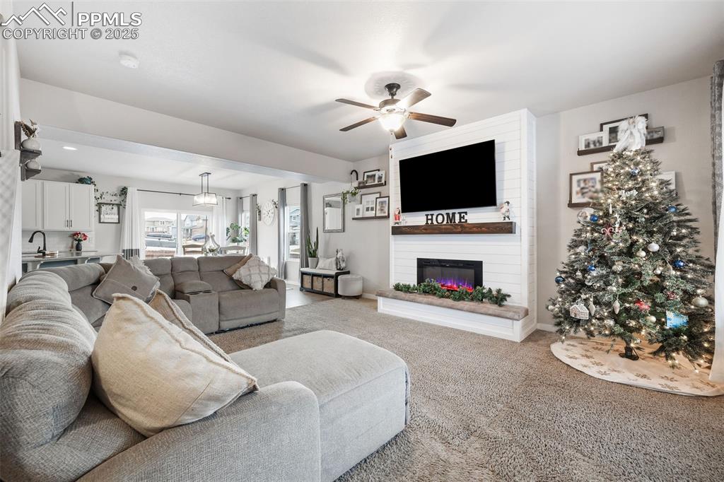 Image 6 of 43: Living room with carpet floors, a ceiling fan, and a fireplace