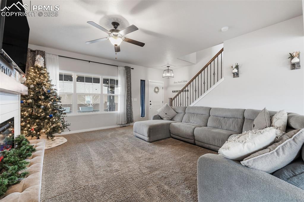 Image 7 of 43: Carpeted living room featuring stairs, a glass covered fireplace, and ceili