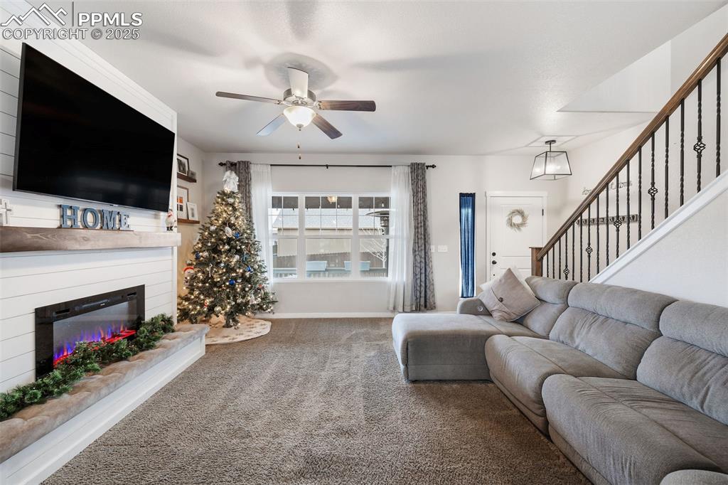 Image 8 of 43: Carpeted living room featuring stairway, a glass covered fireplace, and a c