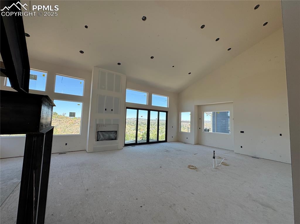 Image 2 of 9: Unfurnished living room featuring a glass covered fireplace and high vaulte