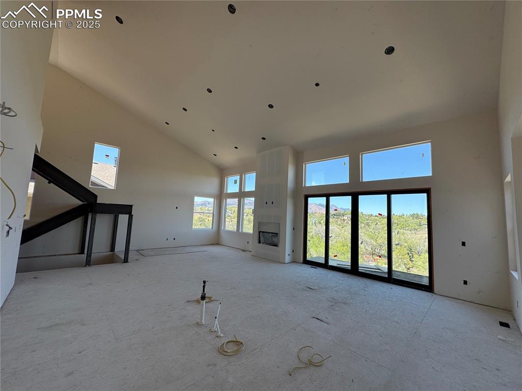 Image 3 of 9: Unfurnished living room featuring a fireplace and high vaulted ceiling