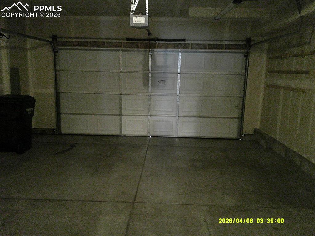 Image 11 of 13: The property features a garage with a panel garage door, concrete flooring,