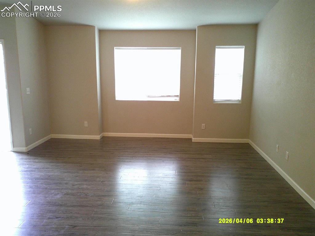 Image 4 of 13: Spacious room featuring wood-look flooring, neutral-toned walls, and multip