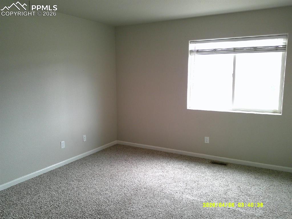 Image 5 of 13: This room features neutral-toned walls, a large window with blinds, and gra
