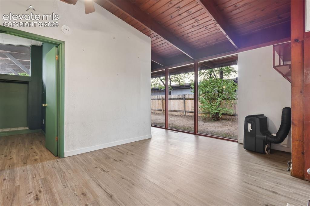 Image 10 of 36: Wood-finish flooring, exposed beam ceiling, full-height windows, and a gree
