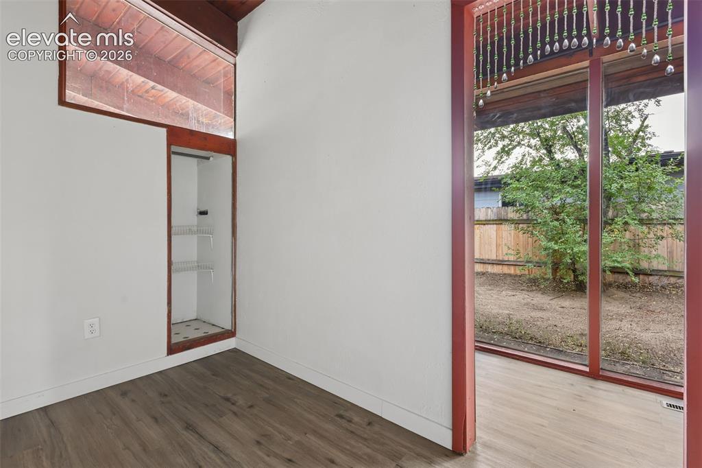 Image 11 of 36: Expansive full-height window, wood-finish flooring, built-in shelving, vaul