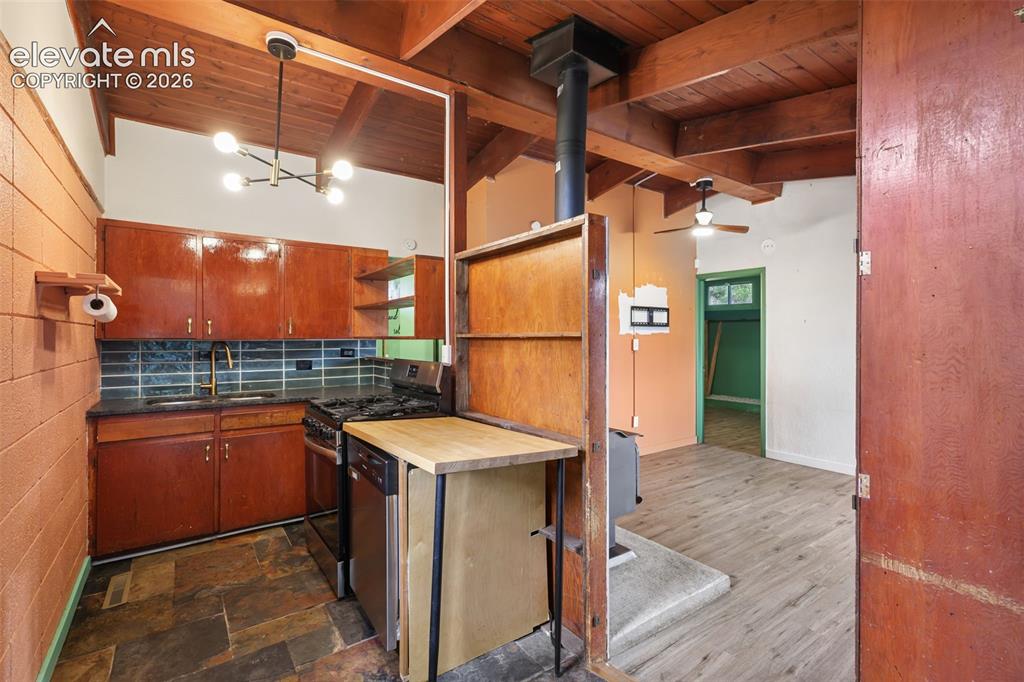 Image 16 of 36: Kitchen featuring wood cabinetry, stone-look tile flooring, and a subway ti