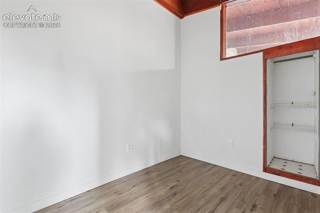 Image 18 of 36: Wood-finish flooring, white walls, built-in shelving, and a wood-framed win