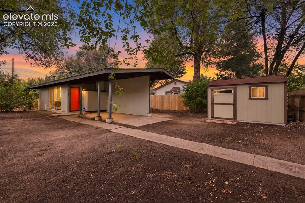 Image 2 of 36: Mid-century modern exterior with a covered entryway and red accent door