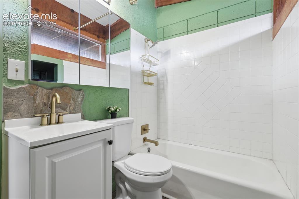 Image 20 of 36: White vanity with integrated sink, brass-finish faucet, and a wall-mounted