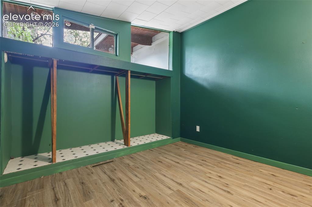 Image 23 of 36: Wood-finish flooring, built-in shelving, high transom windows, and a drop c
