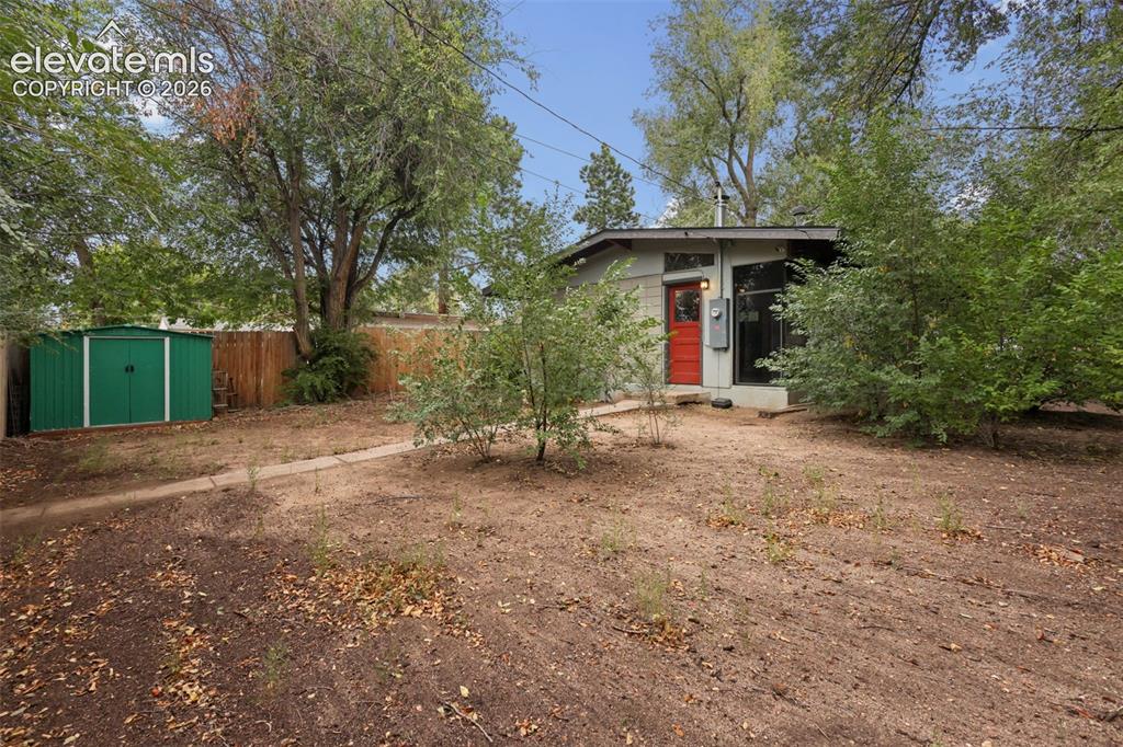 Image 26 of 36: Exterior featuring a red entry door, a detached green storage shed, and a p