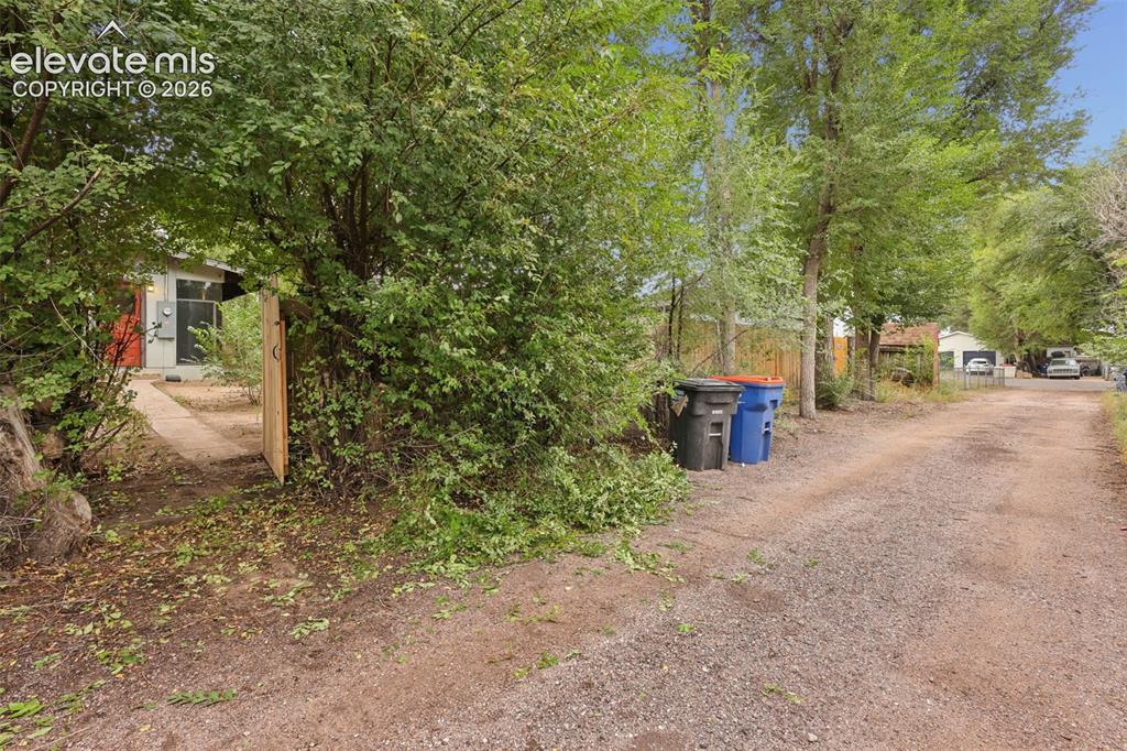 Image 27 of 36: Gravel pathway leading to a residential structure with a red-painted exteri