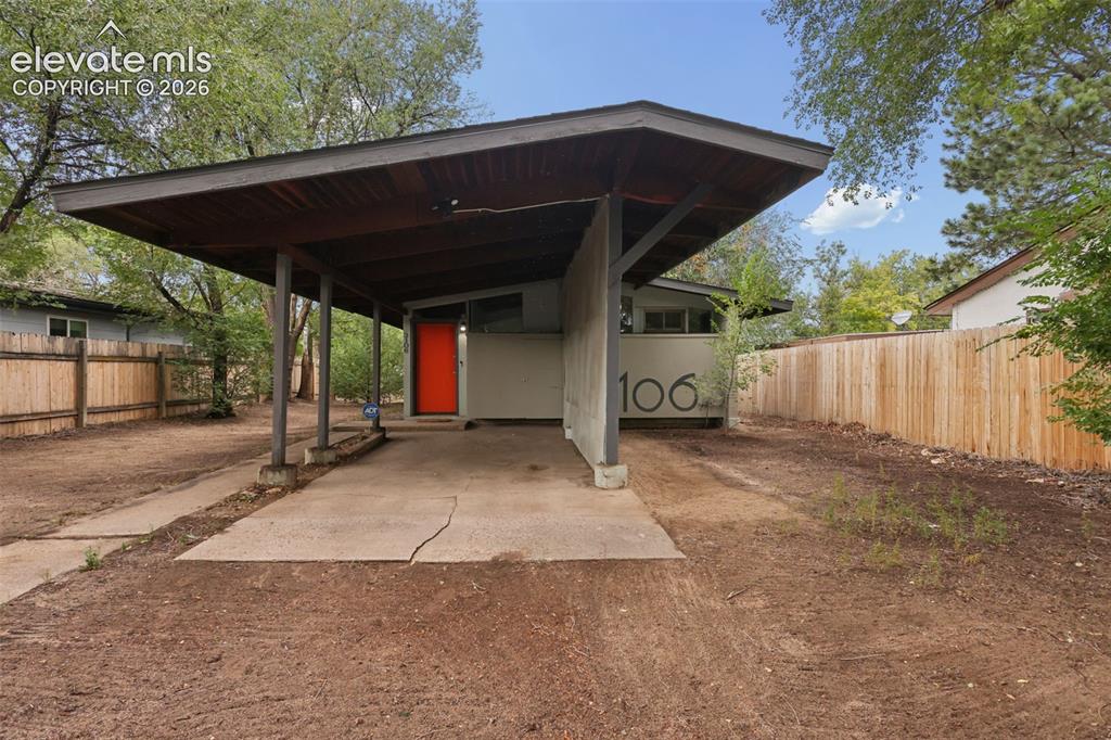 Image 5 of 36: Mid-century modern residence featuring a prominent carport with a wood-fini