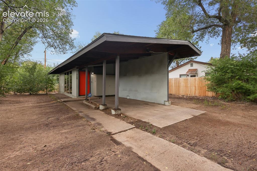 Image 6 of 36: Exterior featuring a covered carport, red entry door, horizontal window ban