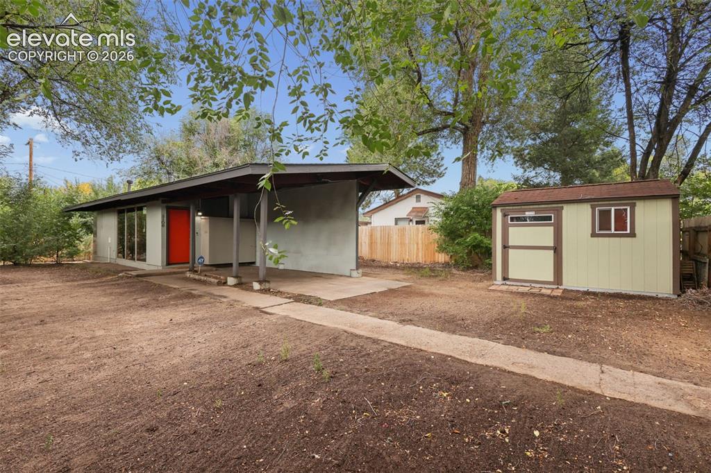Image 7 of 36: Mid-century modern residence featuring a covered carport, bright red entry 