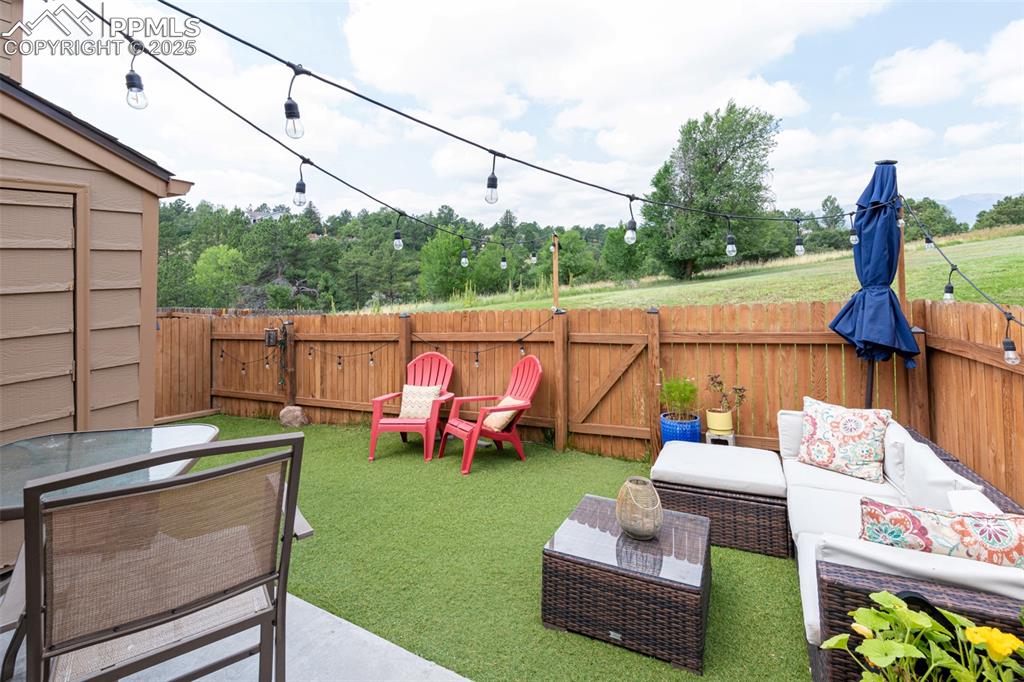 Image 23 of 27: Fenced backyard with outdoor lounge area and a patio