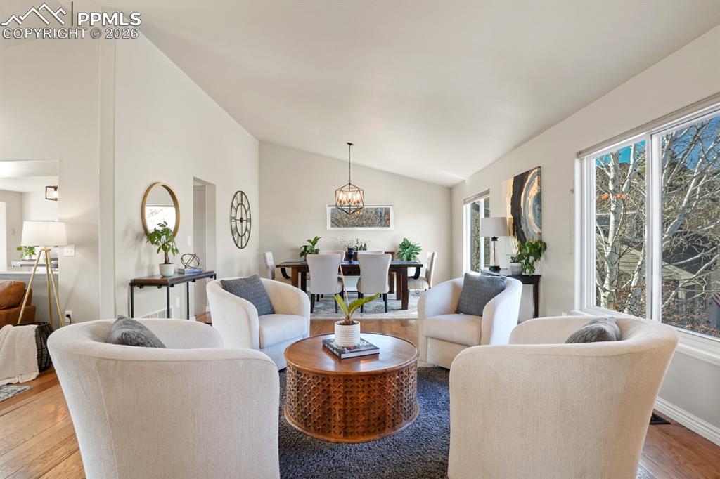 Image 13 of 37: Living room with vaulted ceiling, a notable chandelier, and hardwood / wood