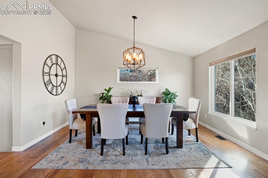 Image 14 of 37: Dining space with lofted ceiling, wood-type flooring, and a chandelier
