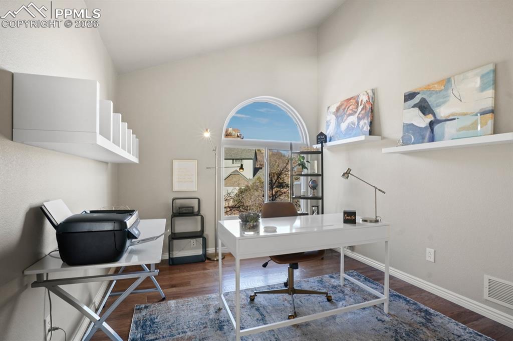 Image 15 of 37: Home office with high vaulted ceiling and dark hardwood / wood-style floori