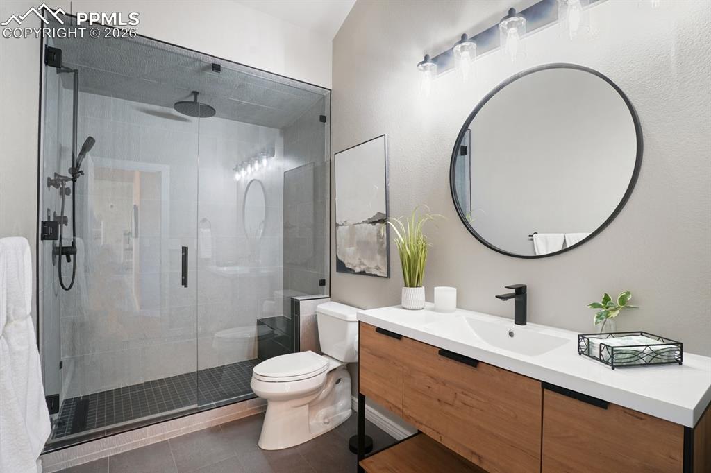 Image 19 of 37: Bathroom with vanity, toilet, tile patterned floors, and a shower with show