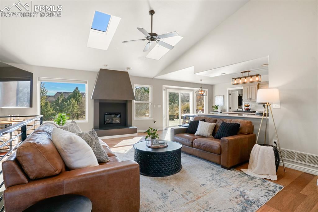 Image 2 of 37: Living room featuring a fireplace, high vaulted ceiling, a skylight, light