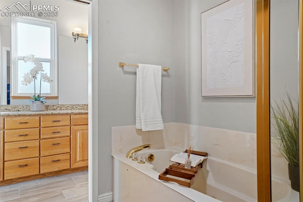 Image 22 of 37: Bathroom with a tub to relax in, hardwood / wood-style flooring, and vanity