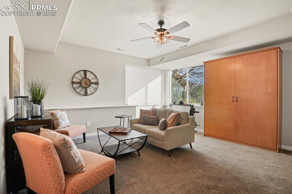 Image 26 of 37: Carpeted living room with ceiling fan