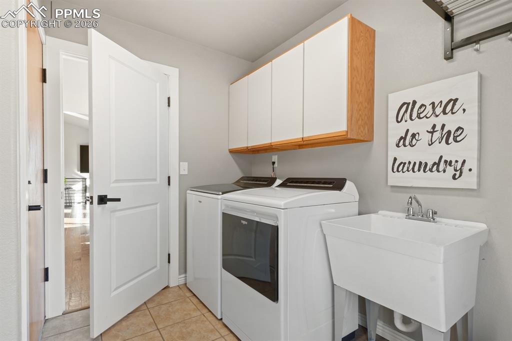 Image 31 of 37: Laundry room with cabinets, separate washer and dryer, light tile patterned