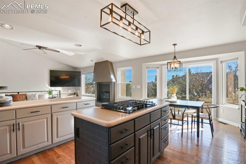 Image 8 of 37: Kitchen featuring ceiling fan with notable chandelier, stainless steel gas