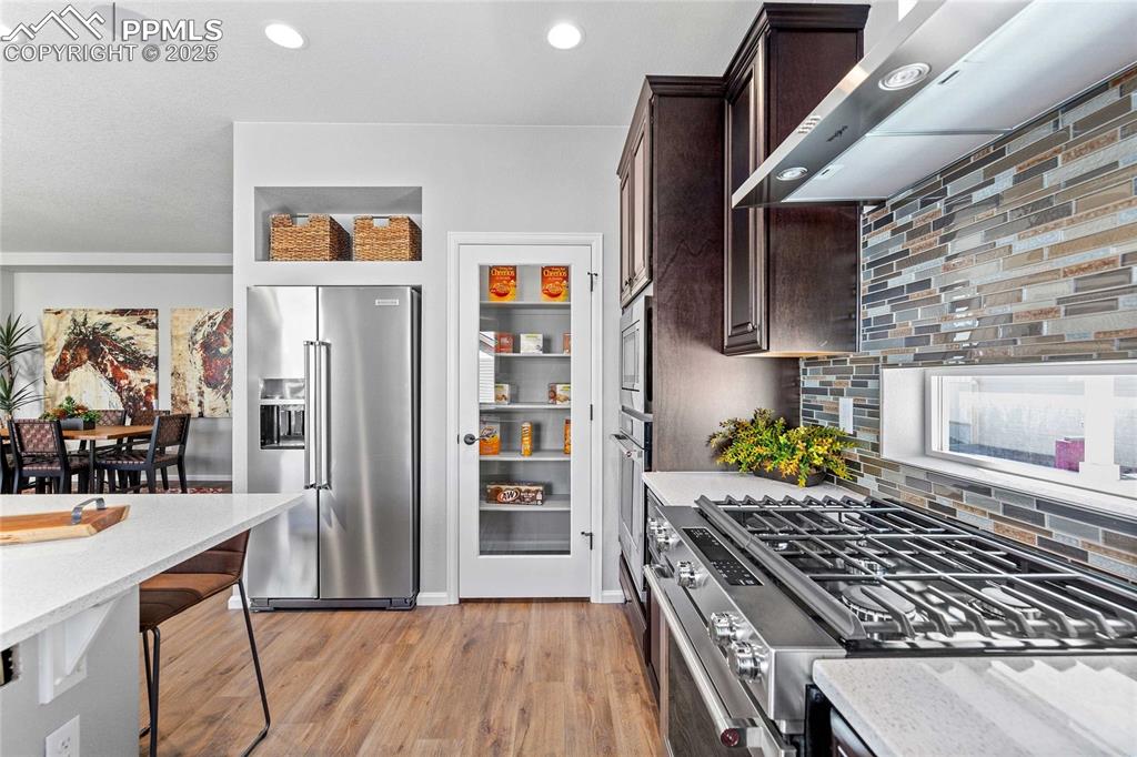 Image 14 of 27: Kitchen with backsplash, wall chimney exhaust hood, stainless steel applian