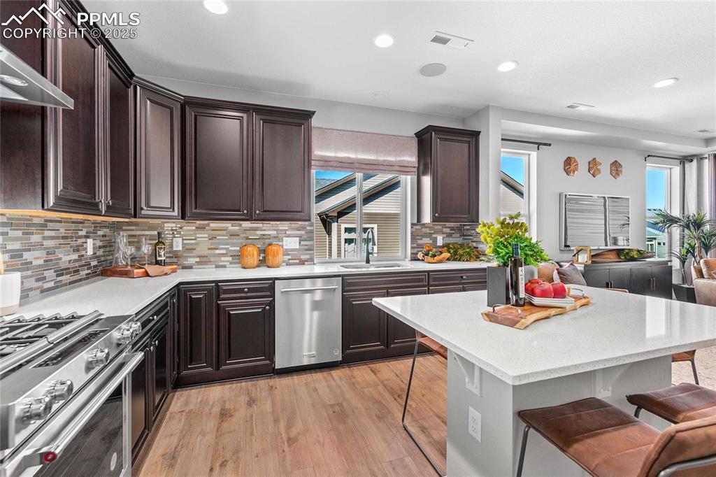 Image 15 of 27: Kitchen featuring a breakfast bar, appliances with stainless steel finishes