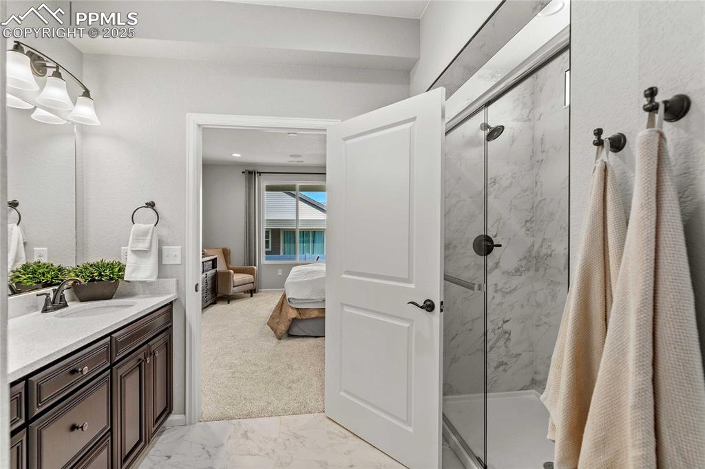 Image 19 of 27: Bathroom featuring a marble finish shower, vanity, light marble finish floo