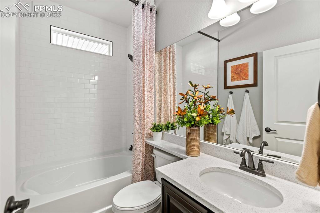 Image 25 of 27: Bathroom with shower / bathtub combination with curtain and vanity