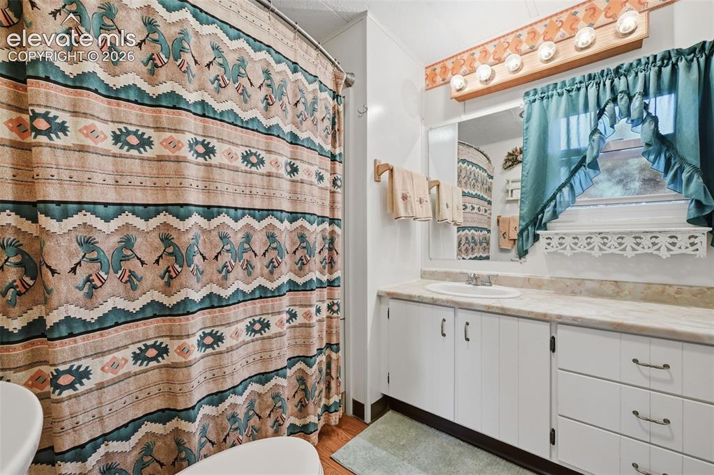 Image 30 of 50: White vanity with extensive cabinetry and drawer storage, a built-in sink, 