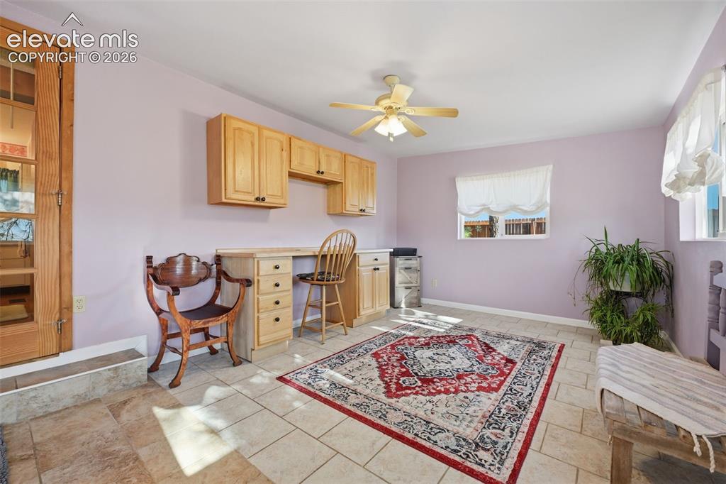 Image 35 of 50: Built-in cabinetry with desk space, ceiling fan with light fixture, tiled f