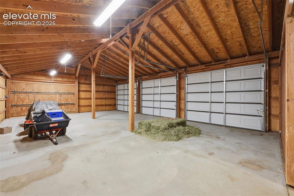 Image 42 of 50: Spacious outbuilding featuring concrete flooring, exposed wood beam ceiling