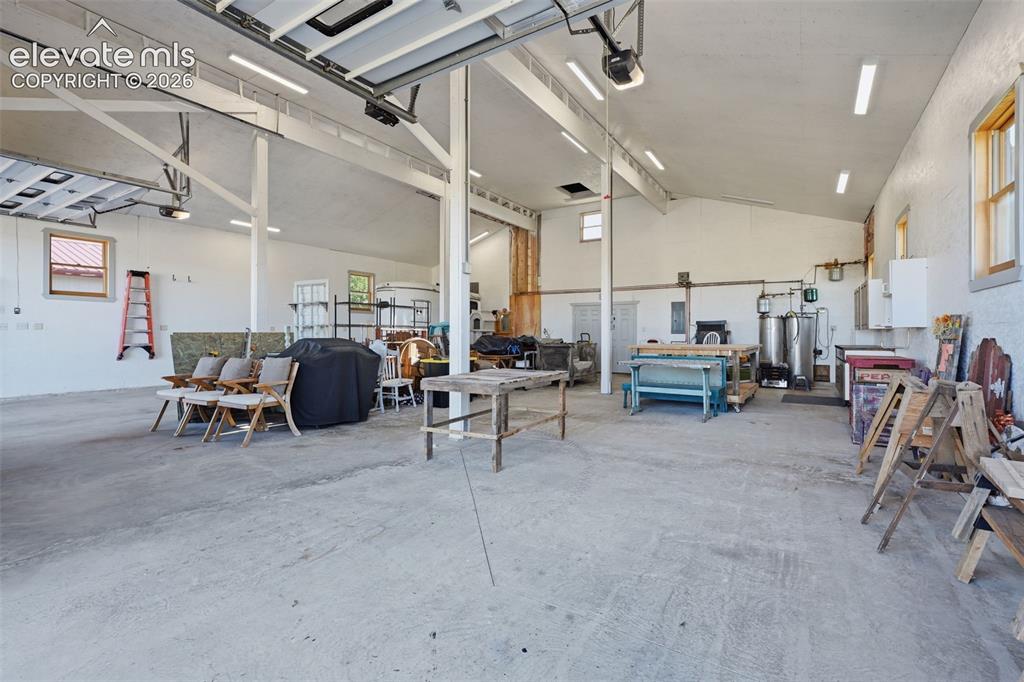 Image 48 of 50: Expansive concrete flooring with exposed beam ceilings, multiple windows, a