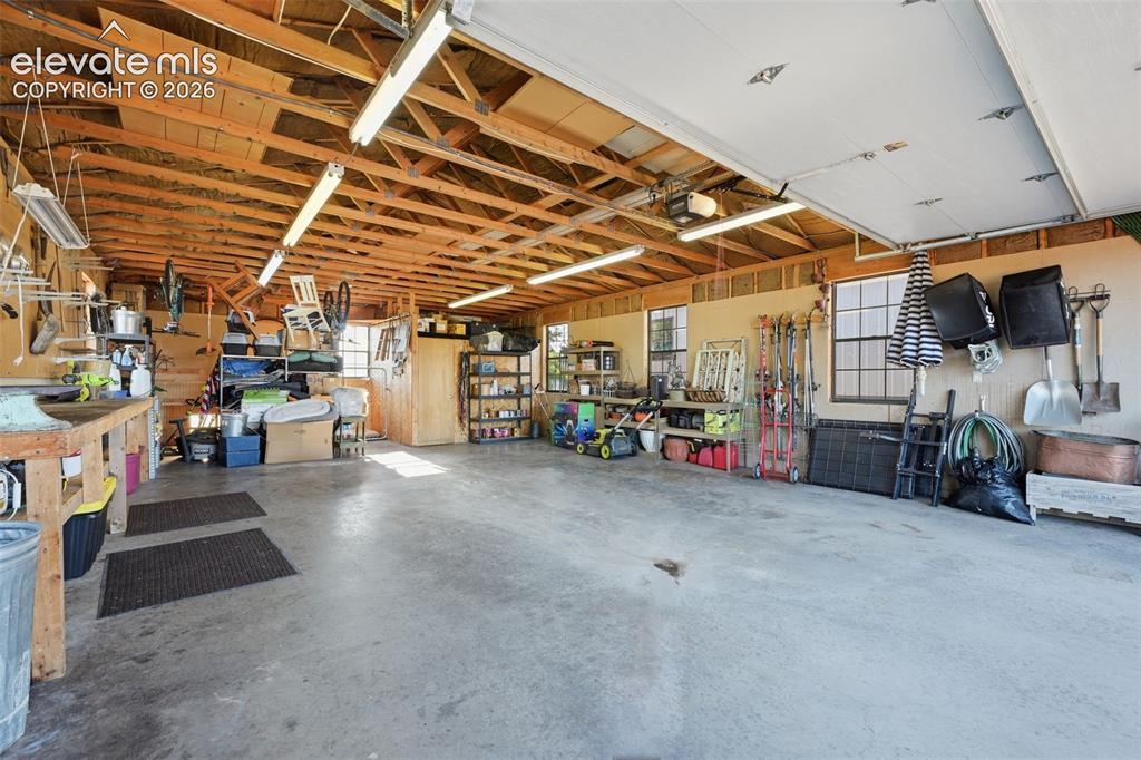 Image 49 of 50: Spacious garage featuring a concrete floor, exposed wood beam ceiling, and 