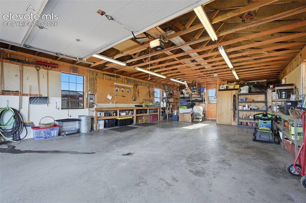 Image 50 of 50: Spacious garage with exposed wood beam ceiling, concrete flooring, and mult